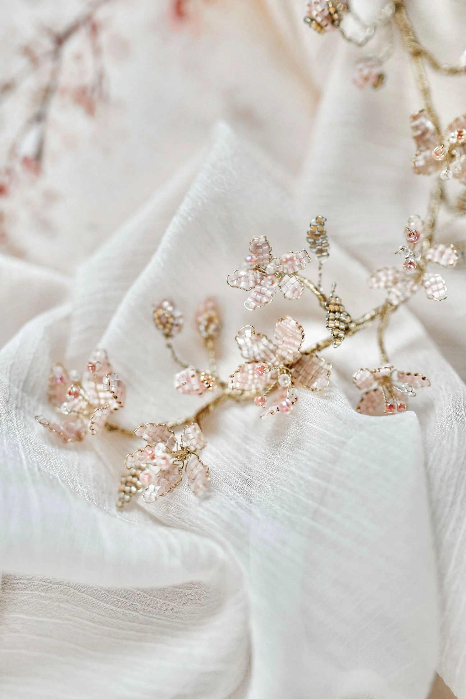 Delicate floral accessories on draped white fabric.